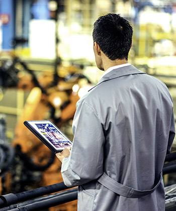Tedarik zincirlerini basitleştirin  man surveying a workspace and holding a tablet